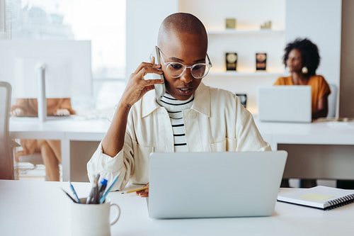 Focused businesswoman at modern office talking on smartphone