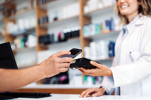 Female pharmacist getting an nfc payment in a drug store