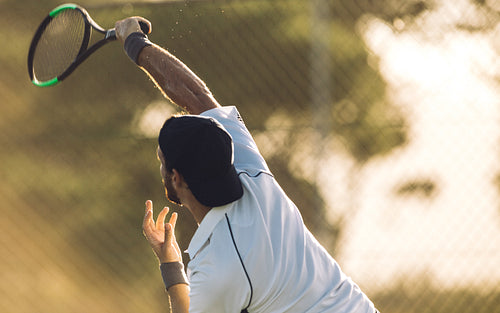 Male tennis player swatting the ball