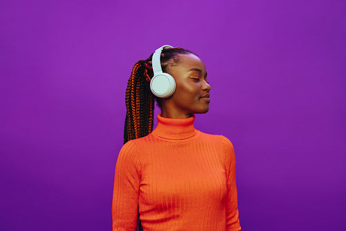 Happy african woman listening to music with headphones in studio