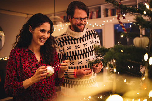 Couple decorating Christmas tree at family home