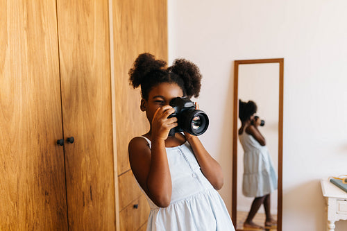 Creative afro-haired girl photographing a moment at home with a digital camera