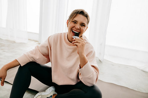 Nutrition matters as the woman eats a protein bar on her yoga mat after exercise