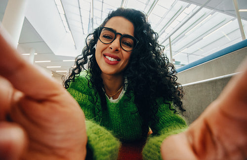 In bright natural light, a woman with glasses shares a smiling indoor portrait