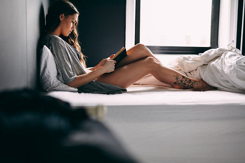 Pretty young lady reading a book on bed