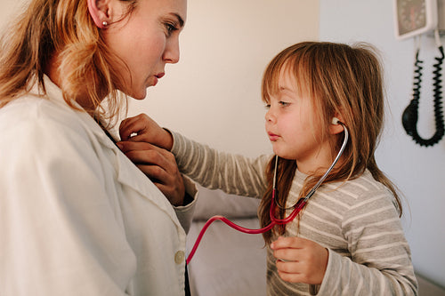 Girl pretending to a doctor examining her pediatrician