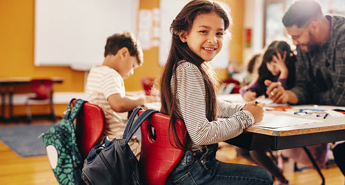 Enjoying an art and creativity class. Young girl smiling at the camera in a classroom