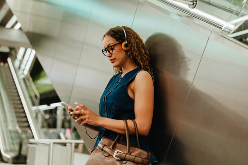 Young woman with headphones checks smartphone during city transit