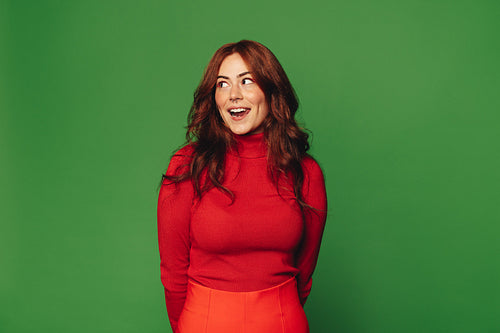 Cheerful woman with a vibrant smile standing against a green background