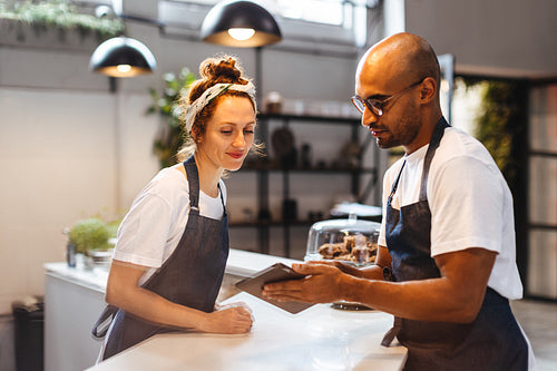 Two hospitality workers using a tablet to manage orders at work