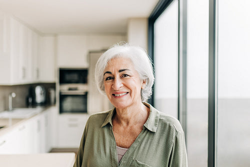 Happy elderly woman smiling cheerfully in her home