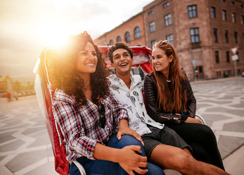 Three young people having fun on tricycle in the city
