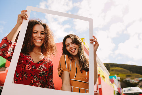 Friends holding picture frame outdoors
