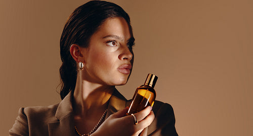 Woman holding perfume bottle in warm editorial portrait