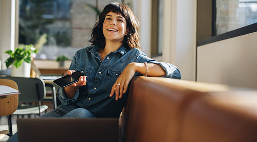 Happy freelancer sitting on sofa in coworking space