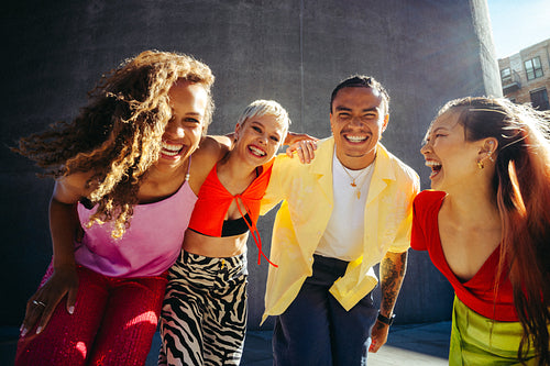 Urban friends laugh together in a city portrait outdoors