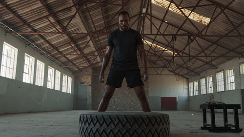Strong man flipping heavy tire at gym
