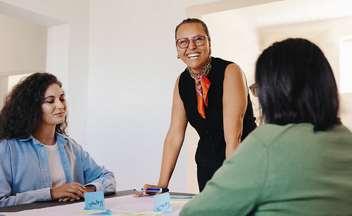 Smiling professional woman leading a meeting with notes and teamwork