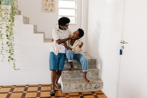 Happily married: Mature couple smiling and holding each other by an indoor staircase