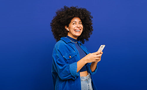 Woman with curly hair enjoying some music on her smartphone