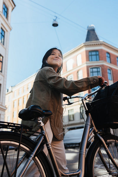Young woman with bicycle exploring a sunny city street