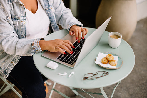 Female nomad digital using laptop at cafe table for remote work
