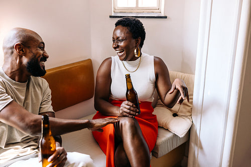 Two stylish friends enjoying drinks, laughing and conversing in a casual setting