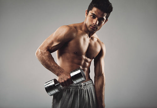 Hispanic young man working out with heavy dumbbell 