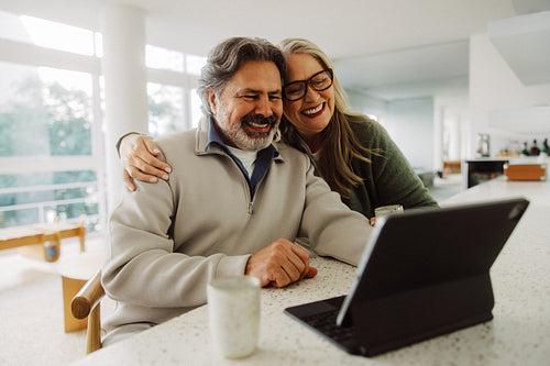 Senior couple video calls on a tablet in kitchen