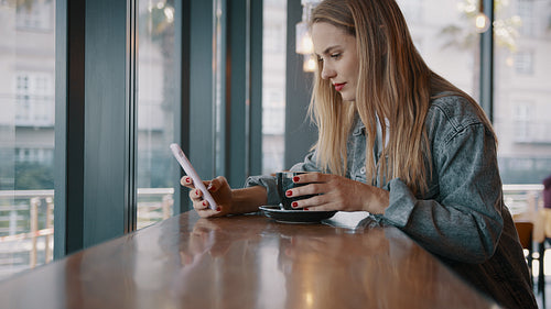 Woman texting in phone and smiling at coffee shop