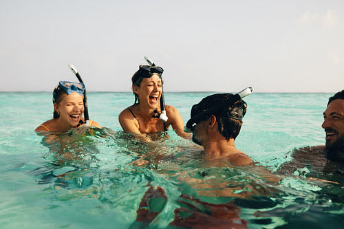 Group of friends snorkeling and laughing in clear blue tropical waters