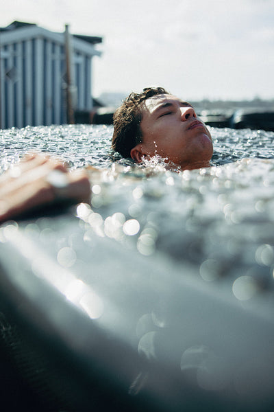 A breathwork recovery session shows a man resting in cold water outdoors.