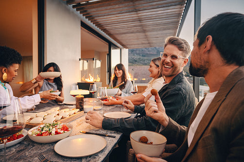 Friends enjoying an outdoor dinner around a table with delicious food and laughter