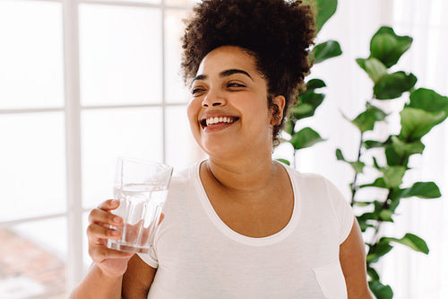 Smiling woman drinking water at home