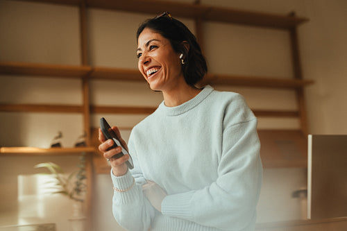 Creative businesswoman laughs with phone in minimalist modern of