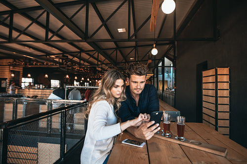 Couple at the bar using mobile phone