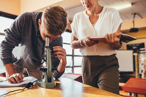 Student with teacher in school laboratory looking in microscope