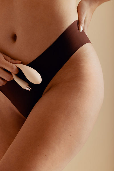 Confident woman exploring her sexual desire with a wearable vibrator in a studio setting