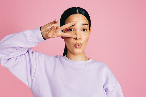 Radiating peace and positivity, young woman doing a peace sign in a studio