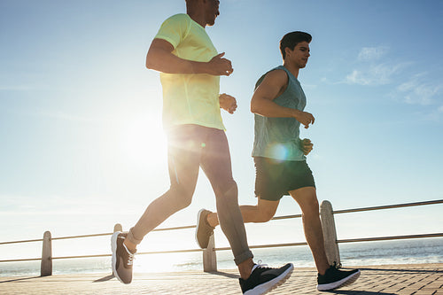 Two young men running on sea front