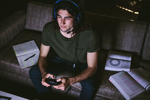 Student playing video game sitting on couch at home