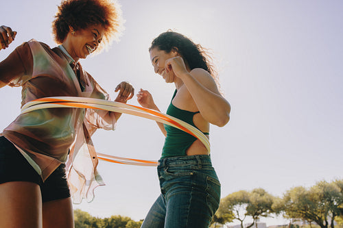 Friends having fun with hula hoops in the park