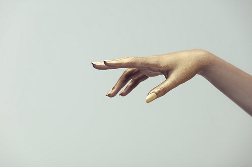 Hand of woman painted with golden color