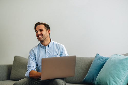 Happy freelancer man using laptop in lobby