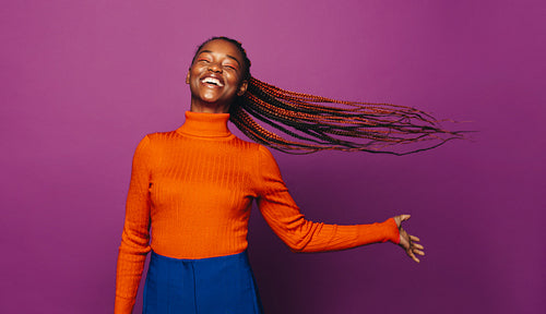 Confident gen z woman with two tone braids celebrating on a vibrant colored background