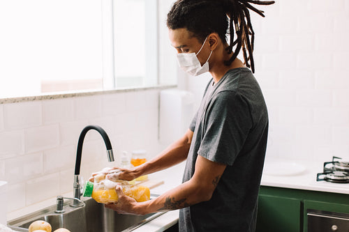 Man with face mask disinfecting groceries at home
