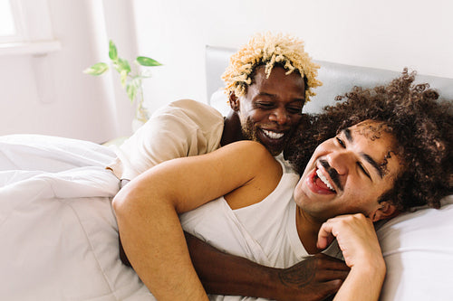 Smiling gay couple lying in bed together