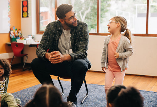 Are you ready to speak in front of the class? Confident little stands next to her teacher ready to do an oral presentation