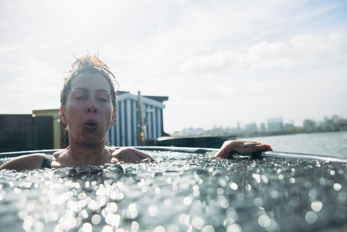 Woman in cold water ice bath for recovery, wellness, therapy, and outd ...