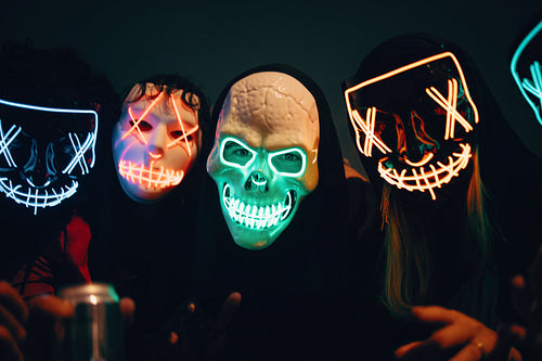 People wearing glowing neon masks together at a dark party